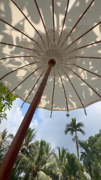 White lace parasol rotates in the wind on the beach on the island of Bali, Indonesia