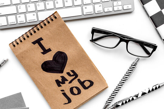 I love my job written in notebook at office desk on white background top view