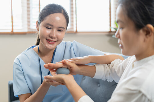Professional physiotherapist assisting senior patient with hand rehab workout using squeeze stress ball at home medical care service concept
