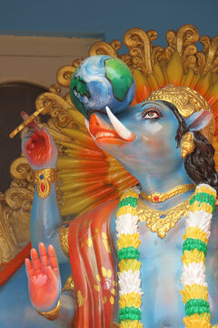 Vertical close-up portrait of colorful Hindu god Varaha avatar of Vishnu lifting the Earth planet on his tusks.