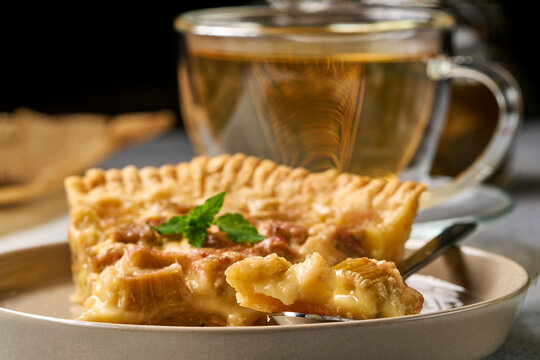 apple pie served with tea on a ceramic plate in a cozy indoor dining setting, top-down view, comforting and warm atmosphere, brown and white colors, natural light, clean background, food.