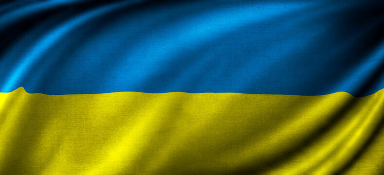 Bright blue and yellow fabric waves in the wind showing the symbol of Ukraine during a sunny day