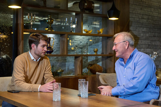 Business Conversation Between Young Professional and Older Mentor in Cozy Cafe Setting, Generational Mentorship