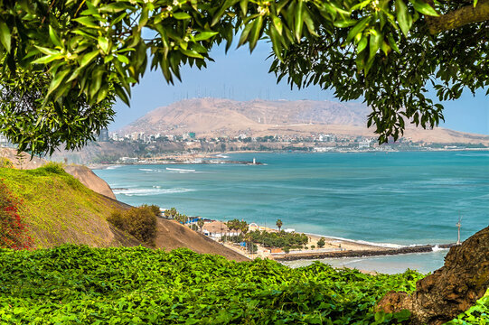 A tree framed view down the coast towards the Morro Solar headland in Lima, Peru in the dry season