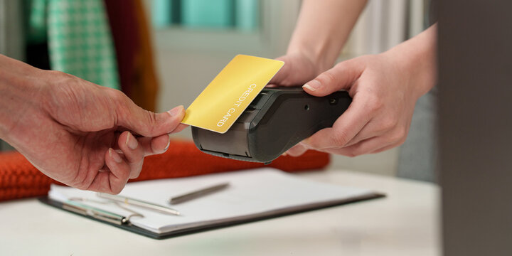Close up of customer tapping credit card on POS terminal for contactless payment