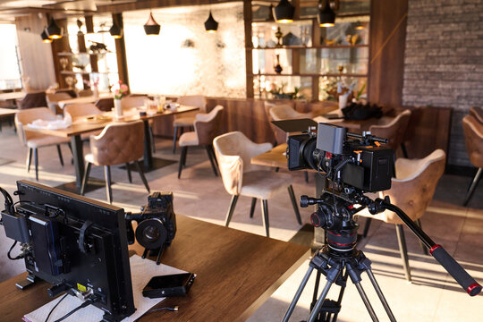 Professional Camera Filming In Cozy Restaurant Cafe Interior With Tripod Monitor And Production Equipment