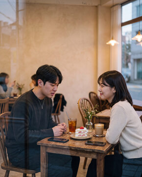 Young couple talking in a cozy cafe over coffee and cake for romantic banner or lifestyle background design