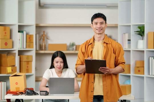 Asian small business owner holding clipboard in warehouse for e-commerce inventory