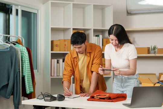 Asian small business owners managing online store with smartphone technology and digital e-commerce tools
