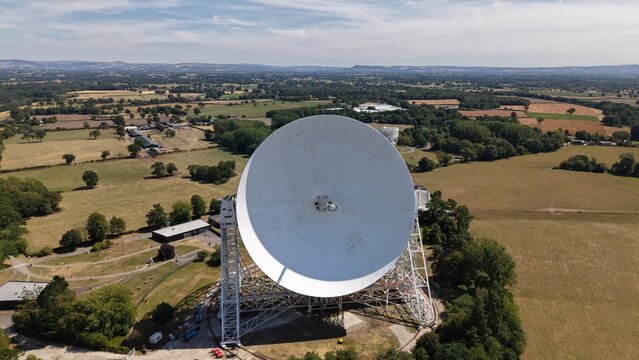 Cheshire, United Kingdom - 08 August 2026: Aerial view of the Lovell Telescope at Jodrell Bank Centre for Engagement, a massive white radio telescope dish set within lush green fields.