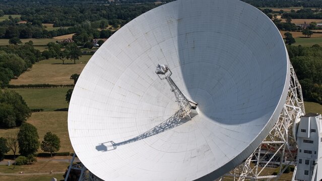Cheshire, England, United Kingdom - 08 August 2026: Aerial view of the Jodrell Bank Observatory radio telescope, featuring its massive white dish set against rural green fields.