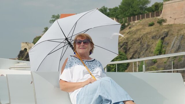 Senior woman rests on a boat deck enjoying a comfortable retirement. Secure pension savings and private investment capital guarantee financial independence, peace of mind, and rich lifestyle.