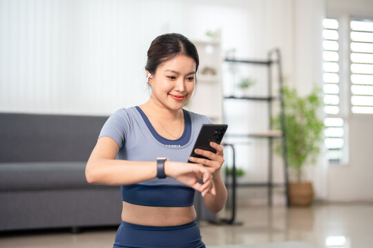 Fitness woman with smart watch and phone indoors.