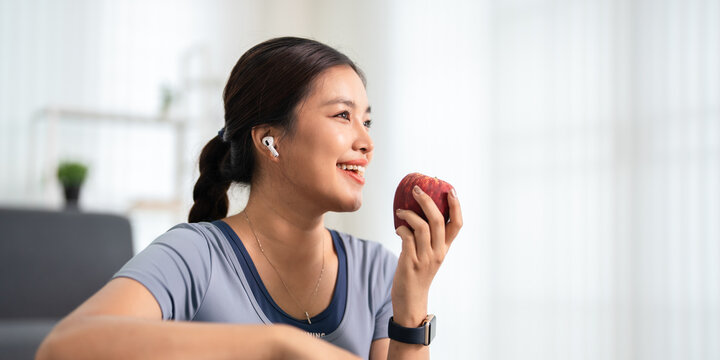 Healthy young woman having apple after work out at home, sport and healthy food lifestyle concept.