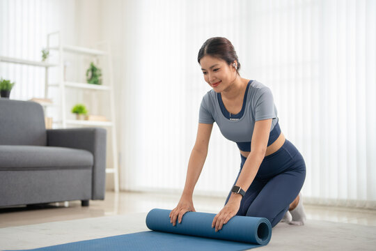 Young woman rolling  fitness or yoga mat . working out at home in the living room .