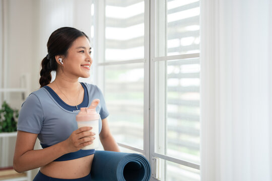 Sporty young woman drinking protein shake at home.