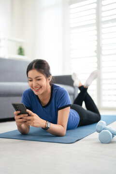 Woman in sport wearig , earphones and phone at home.