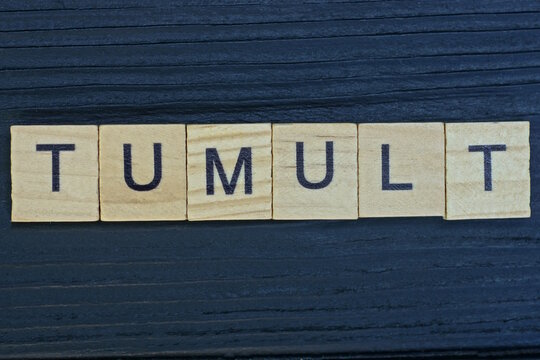 text on word tumult from gray wooden letters on a black background