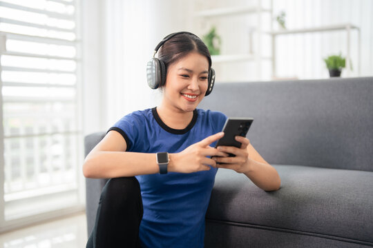 Woman in sport wearig , earphones and phone at home.