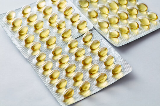 Golden fish oil gel Omega capsules in silver blister packs