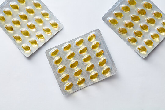 Yellow softgel capsules Omega 3 in blister packs on white background