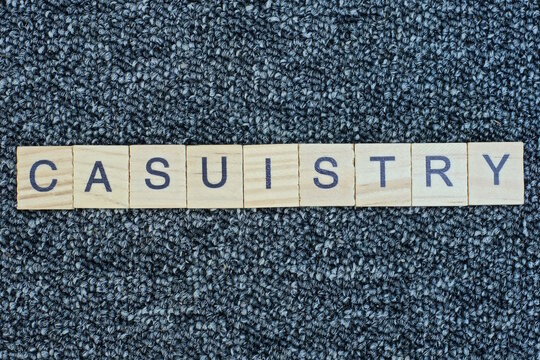 text the word casuistry from wooden small letters with black font on an gray table