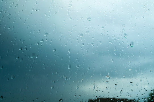 Water droplets clinging to window glass with a stormy overcast sky in the background