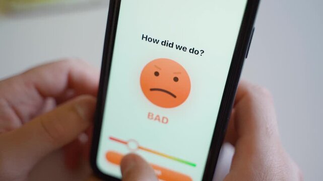 Hands holding smartphone with service feedback app showing smiley face rating