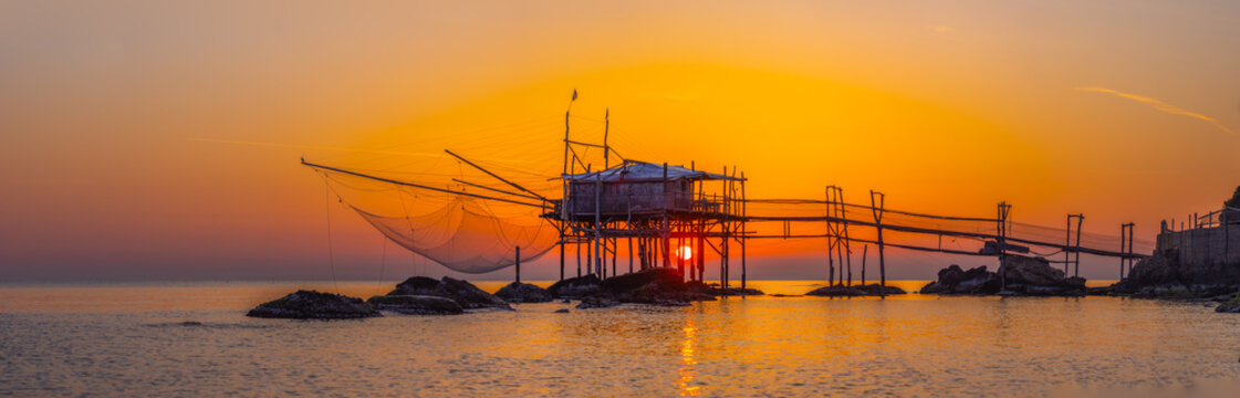 View of Costa dei Trabocchi, a traditional wooden fishing structure on stilts with nets at sunset, located in Marina di San Vito, Abruzzo, Italy.