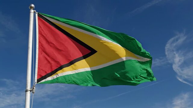 Guyana flag waving proudly against a clear blue sky with wispy clouds