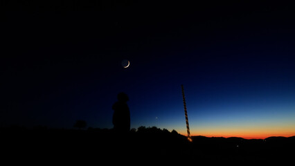 Silhouette of a person in nature observing night sky, Moon, stars and planets from a remote location. © astrosystem