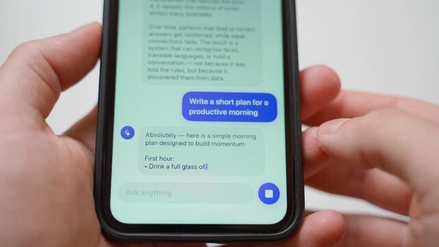 Hands holding smartphone typing prompt about productive morning plan to AI chatbot and reading answer