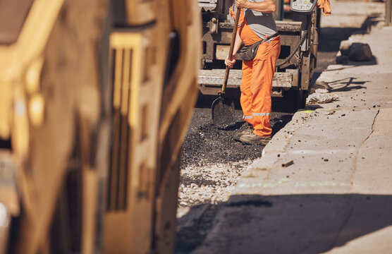 Construction workers working on a new asphalt layer on a public street.