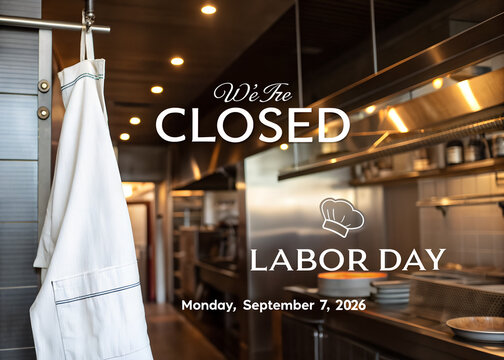 We are closed sign for labor day with a white chef apron hanging in a professional restaurant kitchen background