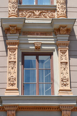 Fototapeta premium A close view of an old classic building facade features a glass window beautifully framed by rectangular pilasters with intricate stone carvings and floral reliefs in Zagreb, Croatia