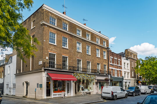 View of a historic brick building with retail shops and a red awning in the Belgravia neighborhood of London, England, United Kingdom.