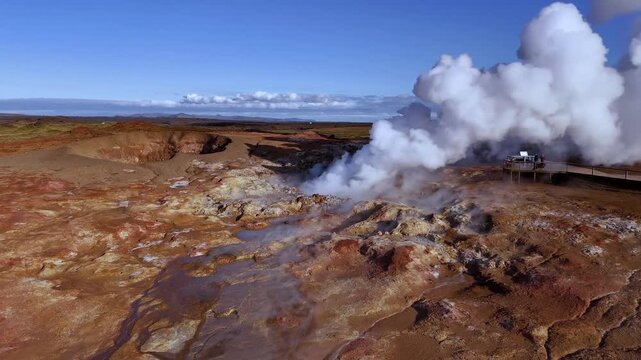 Aerial drone view of a steaming geothermal field near Lake Myvatn in North Iceland featuring active steam vents mineral rich ground hot springs and visitors on a wooden walkway