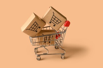 Small shopping cart with cardboard boxes on beige background shopping ecommerce delivery cardboard © mrzn