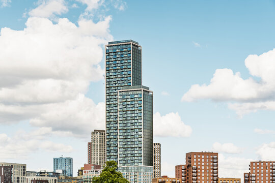 View of modern high-rise residential towers in Acton with glass facades and balconies under a blue sky with white clouds in London, England, United Kingdom.