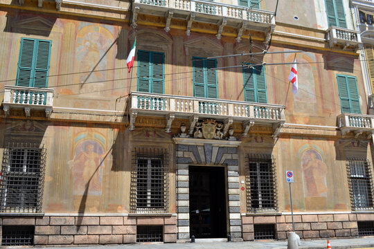 Ornate frescoed palazzo facade with green shutters and italian flags in Genoa for architectural background and heritage banner