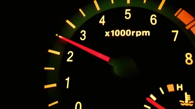 Close up of a car tachometer needle rising quickly representing engine revs, speed, acceleration, automotive performance, vehicle power metrics