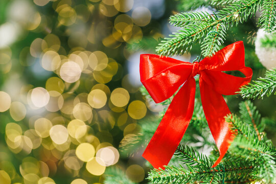 Red bow on Christmas tree with festive golden lights