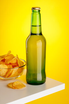 Beer bottle and chips on yellow background snack setup