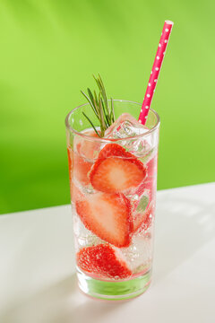 Fresh strawberry infused water with herbs on green background with copy space