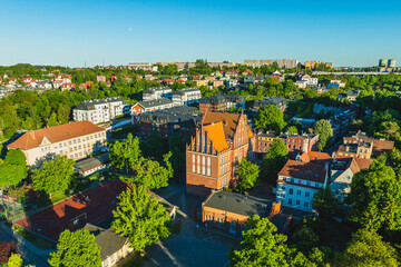 Aerial view of Siedlce district in Gdańsk, Poland, with residential buildings, a historic church, roads, tram tracks and abundant greenery. © Kamil