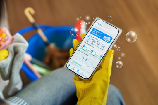 Person holding smartphone with cleaning service app for home maintenance booking