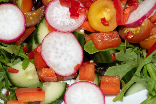 Close up of a delicious healthy side salad with leaves and radish on a white plate