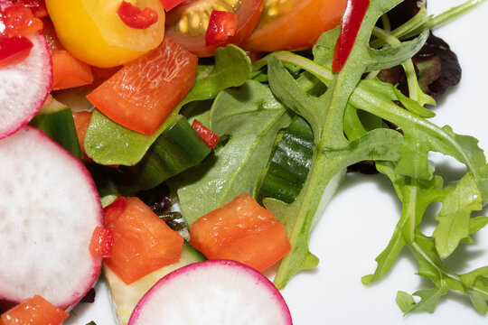 Close up of a delicious healthy side salad with leaves and radish on a white plate