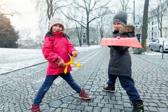 Portrait two cute little kids boy girl enjoy having fun playing with snow toys city street park  family on snowy cold winter day. Children carefree joy walk outdoors. Happy childhood healthcare