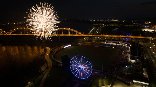 Aerial view of fireworks exploding over a baseball stadium with a Ferris wheel and the Centennial Bridge spanning the Mississippi River in Davenport, Iowa, United States.